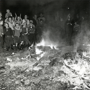 602858 Afbeelding van een groep kinderen rond de brandende resten van een oude woonwagen op het woonwagenkamp aan de ...